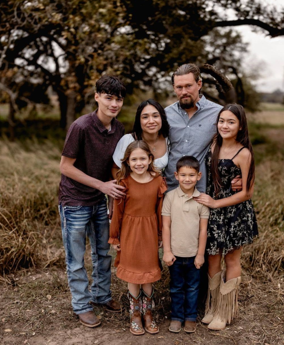 Aurey Kunschik, owner of Dawn Till Dusk Construction, with his family outdoors under an oak tree