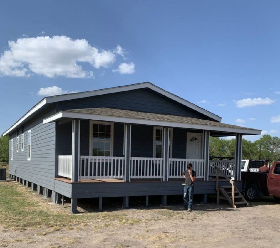 Finished home in blue siding with a white porch rail, covered porch and new steps
