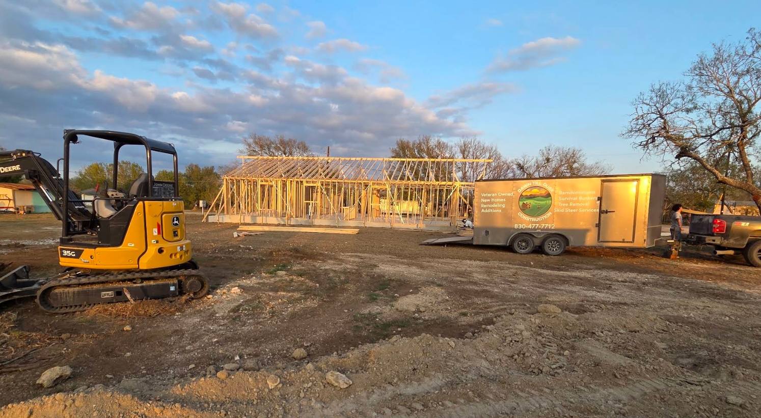 Dawn Till Dusk Construction trailer and excavator on a custom home site at dusk, timber frame up behind